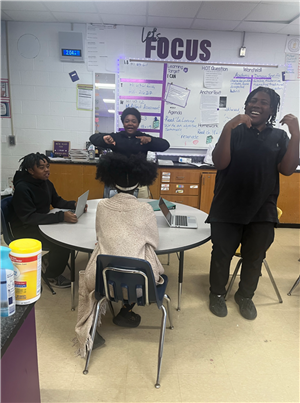 2 male students standing looking excited while 2 students are sitting